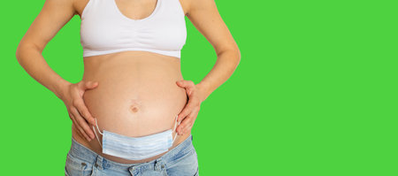Banner of medical mask on the belly of a pregnant girl on isolate background. Concept of pregnancy...