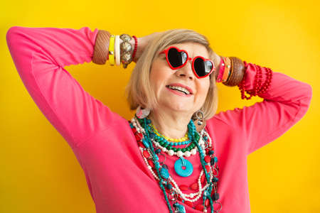 Funny grandmother portraits. Senior old woman having fun in stylish clothes, concepts about senior peopleon colored backgroundの写真素材