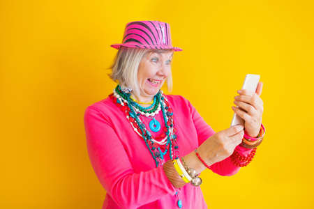 Senior woman talking on smartphone in stylish clothes, concepts about senior people on colored...