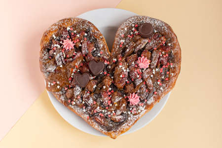 Valentine's Day sweet pizza or pie, with chocolate, caramel sauce, hearts and pecans on a modern...