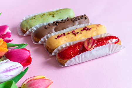 Eclairs and colorful tulips flower composition over pink background . Love, Mothers day, Womens day and spring time flower background. spring nature backgroundの写真素材