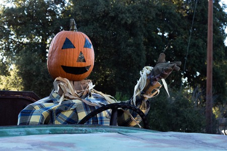 Smiling, happy, welcoming, fun friendly pumpkin head scarecrow driving an old truck to a halloween harvest partyの写真素材
