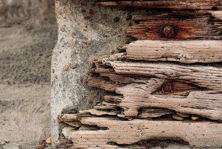 Driftwood with rusted bolts set against a concrete stone wall, vintage grunge backgroundの写真素材