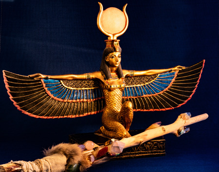 Egyptian goddess kneeling with traditional magic wand made with quartz, amethyst crystals, wood and...
