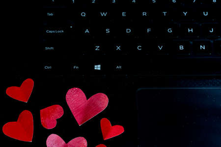 Red painted folded hearts on a laptop keyboard, concept love in the workplaceの写真素材