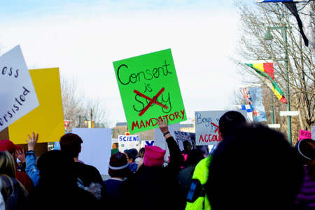 Women's March in Philadelphia PA on the Benjamin Franklin Parkway. Woman holds a bright green sign that reads: "Consent is sexy (crossed out) mandatory"のeditorial素材