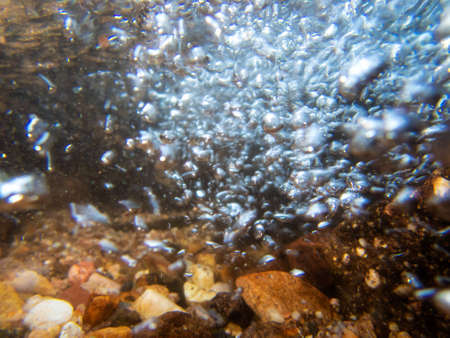 A rush of bubbles swooshes toward the camera in a high energy underwater hydro dynamic image with...