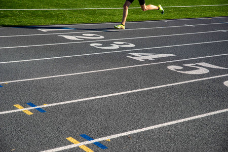 Lone runner crosses large white numbers on athletic racing trackの写真素材