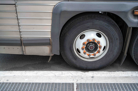 Closeup of city bus wheel tire and the metal side of the bus body with vintage look. Lug nuts and...