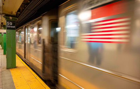 New York City subway station at 59th street underground with green pillar and yellow safety line. Subway train car arriving or departing with motion blurの写真素材