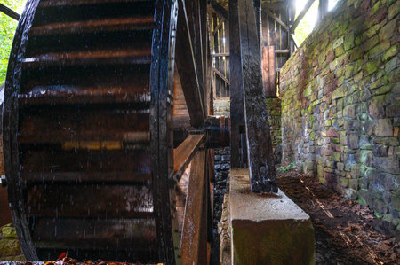 Enormous water wheel turns with shaft and spokes visible, colonial American Pennsylvania industry at...