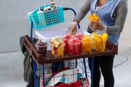 Fresh fruit street vendor fills plastic cups with cut mangoes NYCのeditorial素材