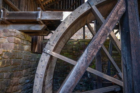 Side view of section of a giant historic water wheel for hydropower with sleuce spillway. Woodgrain...