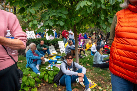 Protesters rest under trees at No Kings political protest rally Philadelphia people signsのeditorial素材