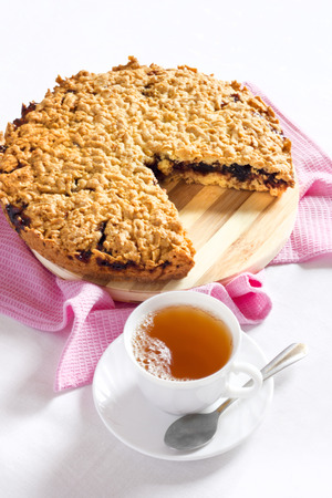 Grated pie with a cup of tea on the table and decorated with pinkの写真素材