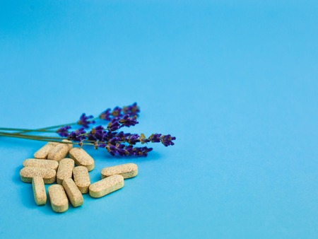 Assorted size and shape yellow pills with lavender on a blue backgroundの写真素材