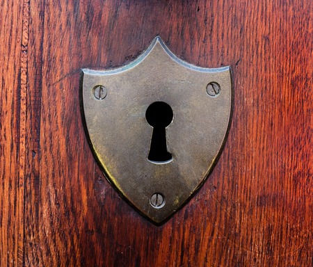 Close-up shot of a scratched keyhole on a wooden doorの写真素材