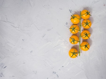 Bunch of yellow cherry tomatoes on gray backgroundの写真素材