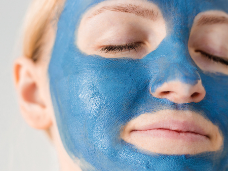 Skin care. Woman face with blue clay mud mask close up. Girl taking care of oily complexion. Beauty treatment.の写真素材