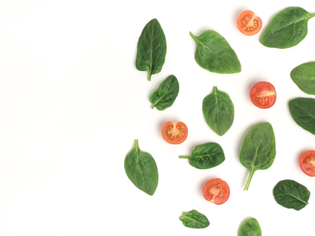 spinach and slices of baby tomatoes on a white background, top view with copy space, mock upの写真素材