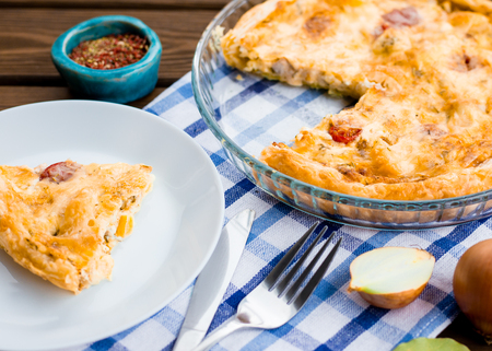 Rustic large tart and piece with cloth on a wooden table, view from above, close-up