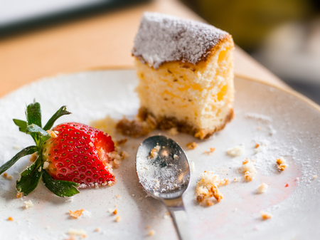 left over cheesecake with strawberry on brown background, selective focusの写真素材