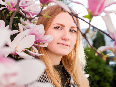 Beauty young woman enjoying nature in spring magnolia garden. Romantic fashion model in blossom...