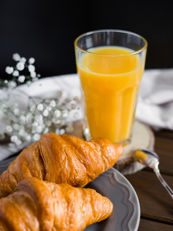 delicious breakfast with croissants, flowers and juice, good morning. Glass of refreshing orange fruit juiceの写真素材
