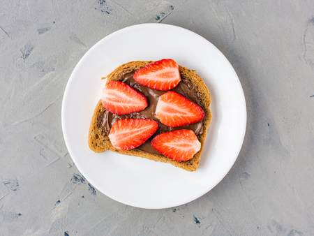 Toast with chocolate and strawberry, Single sandwich with chocolate cheese on white plate, top viewの写真素材