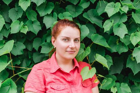 Happy beautiful young woman in leaves grapes, natural background. Gorgeous Woman Face in a park,...