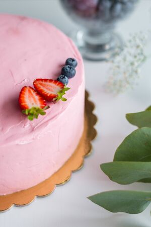 Homemade pink birthday cake decorated with berries: strawberries, blueberries. Girl birthday cream cheese pink cakeの写真素材