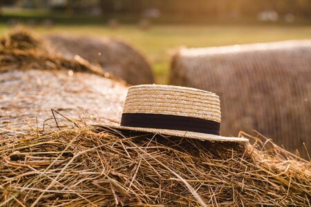 Photo landscape haystack rolls in the field with straw hat. Rustic farming concept. Summer day, sunsetの写真素材