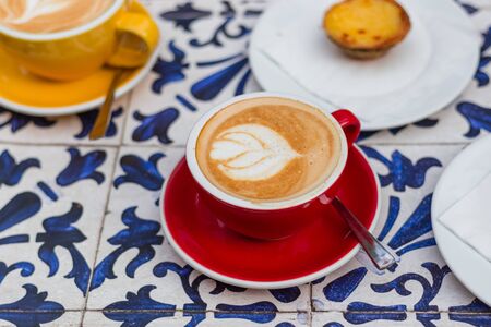 Two Cups of coffee latte in ceramic cups with traditional Portuguese dessert pastel de nata.の写真素材