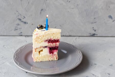 Slice of Birthday Cake with a lit candle over a gray background. Girl cake, Bakery and coocking...
