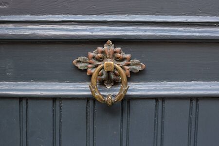 Antique brass door knocker in the shape, door element with metal knob. A very old door handle