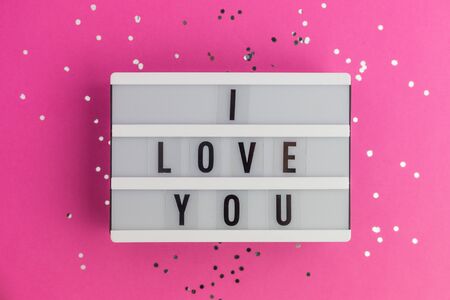 I Love you text on white lightbox. Pink background with multicolored confetti. Flat lay styleの写真素材