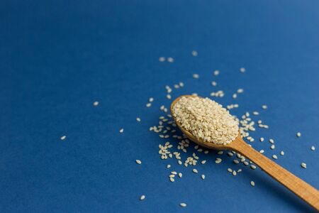 White sesame seeds in spoon on blue background. Color of the year 2020. Healthy food and drink concept. Copy space background. Flat lay style. Top view.の写真素材