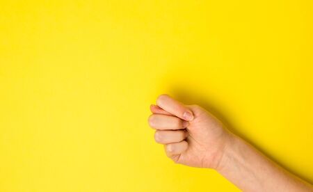 Close-up fig sign. Hand Gesture on yellow background. Flat lay.の写真素材