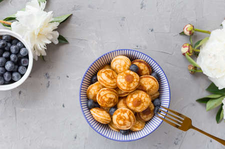 Mini cereal pancakes with blueberries in a bowl on gray background. Trendy food concept, Breakfast time for kids. Menuの写真素材