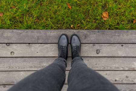 Black shoes standing on the wooden pier. Feet shoes walking in outdoor. Youth selphie hipsterの写真素材