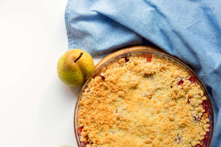 Red berry crumble in glass baking dish with cloth on white background. Close up.の写真素材