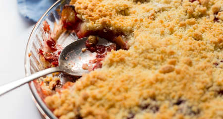 Red berry crumble in glass baking dish with cloth on white background. Close up.の写真素材