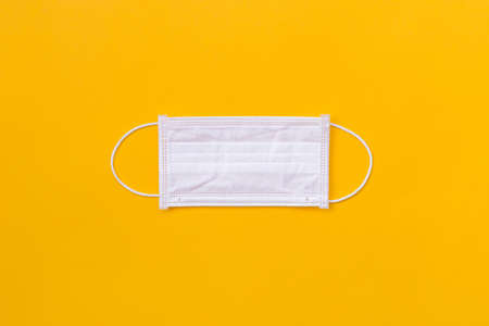 Surgical protective mask on the Yellow background. Healthcare medical Coronavirus quarantine, Concept Of Air pollution, flat lay banner, top viewの写真素材