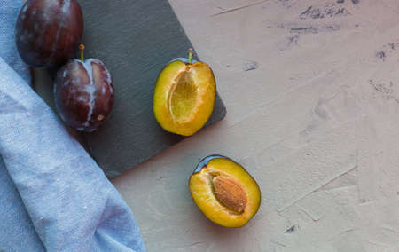 Fresh plums with blue cloth on gray table background.