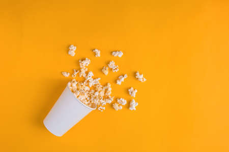 Paper cup with popcorn on yellow background. Flat lay banner, top view. To go to the cinema.の写真素材