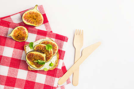 Sandwich with cream cheese, figs, honey and leaves salad served on the cloth on white background....