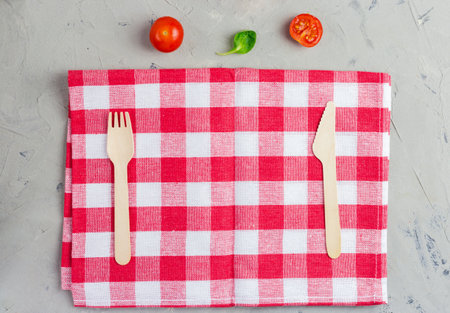 Checkered napkin with knife and fork on gray background. Abstract food background with napkin and wooden cutlery. Napkin close up top view mock up for design. Top view with copy spaceの写真素材