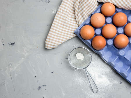 Ingredients for pastries: flour, eggs on gray background