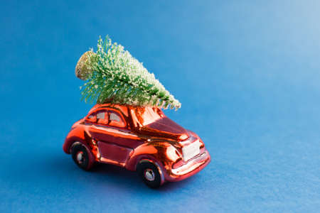 Red toy car with a christmas tree on the roof, blue trend background
