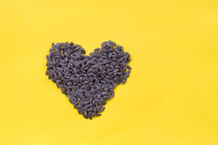 Sunflower seeds in the shape of hearts on yellow background
